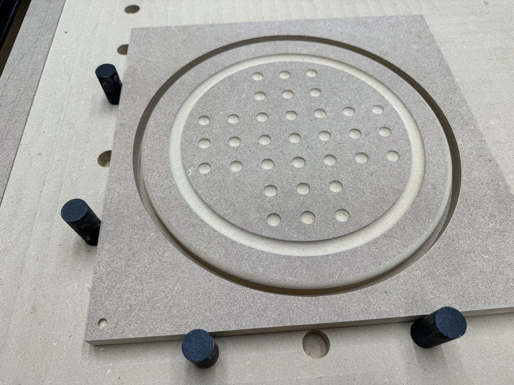 CNC-machined MDF solitaire-board prototype held on the router bed